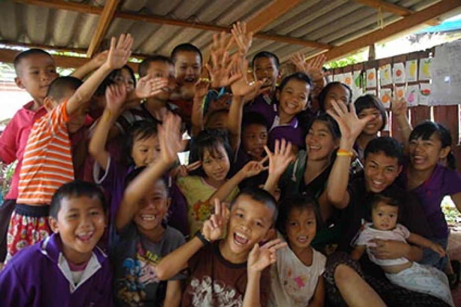 group of smiling happy children posing for the camera with raised hands and peace signs