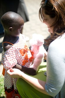 woman giving a stuffed animal to a small girl