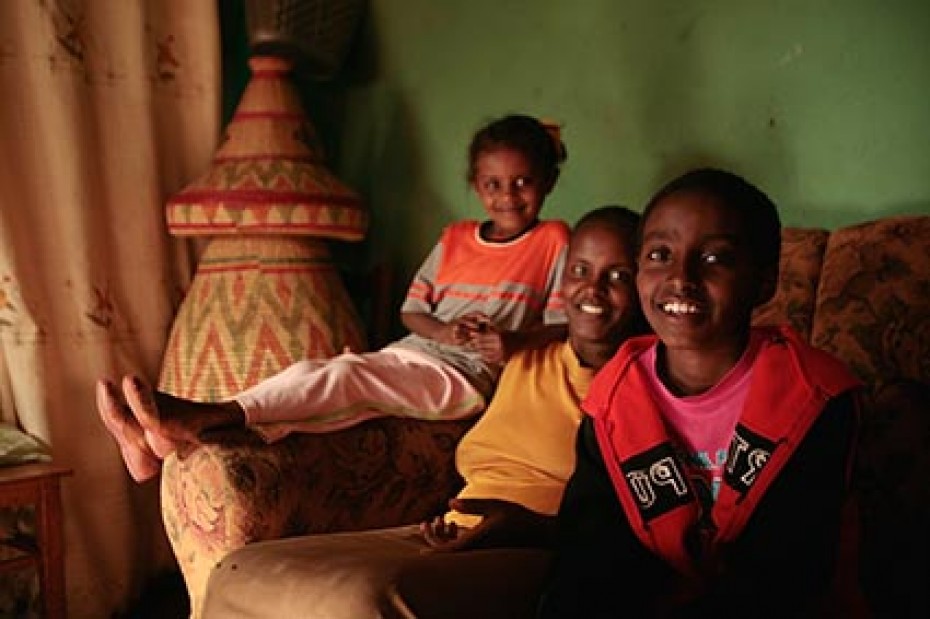 three young smiling children sitting on a couch
