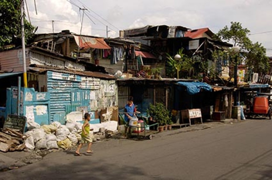 Young child outside of run-down buildings.