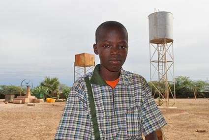 Young boy standing by two towers.