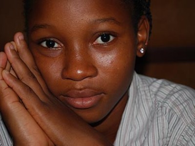 A girl wearing a blue shirt with her hands up against her face