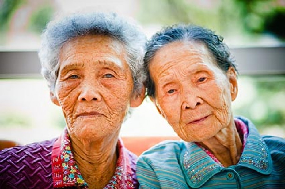 two elderly women with their heads together