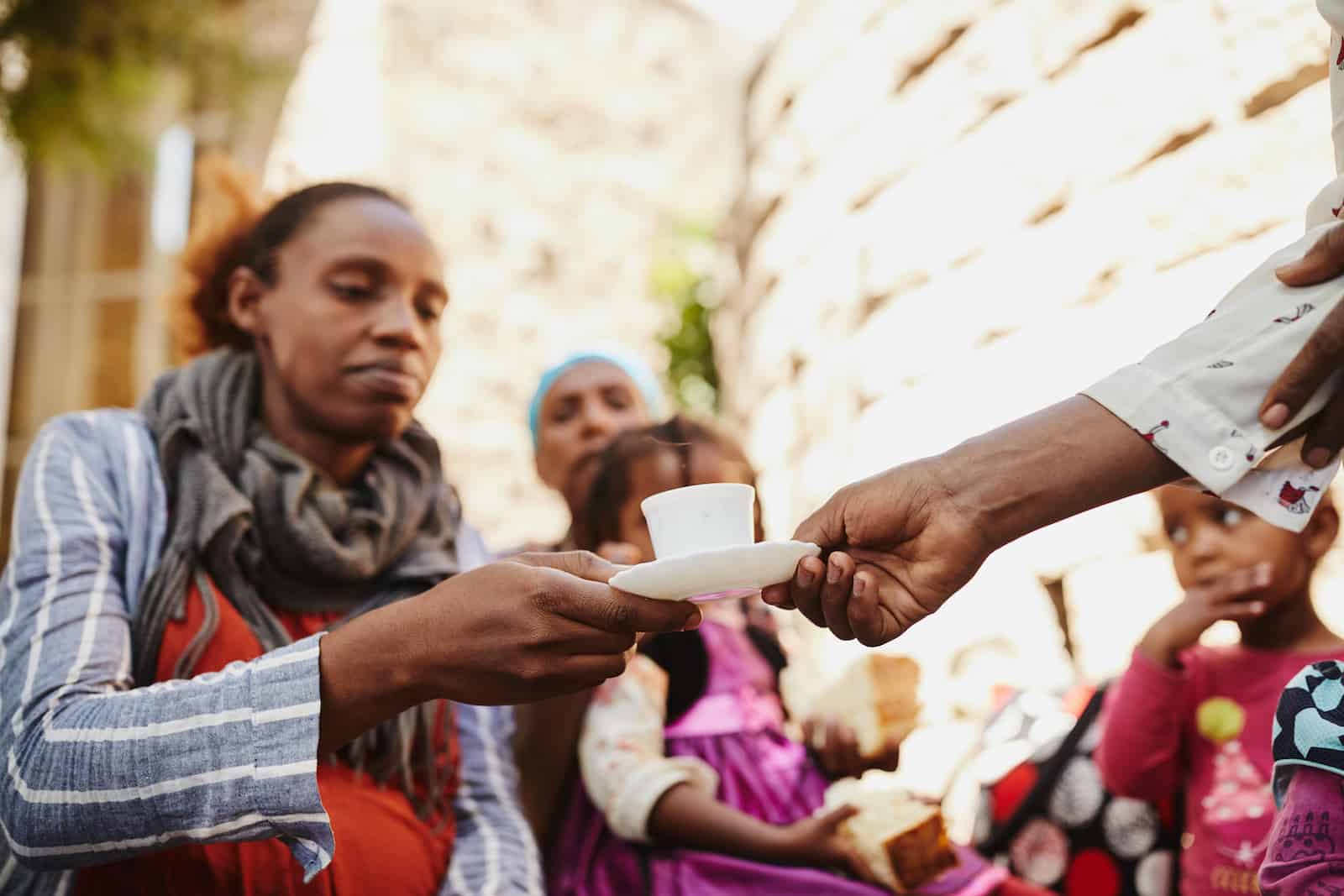 A woman is handed a small cup of coffee.