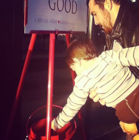 young boy placing money in kettle