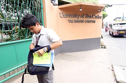 young man looking through backpack in front of university