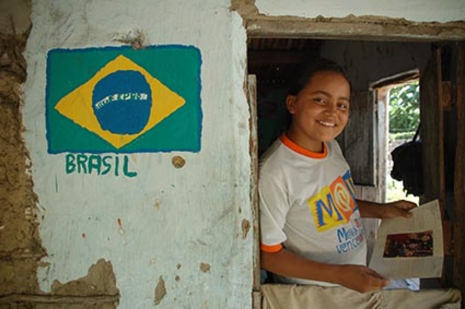 A child leans against a wall with a Brazilian flag on it