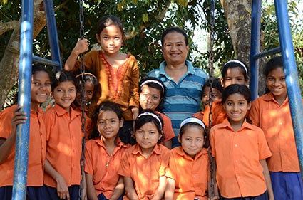 man standing with a group of children wearing orange shirts