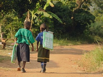 Two children walking on a dirt path.