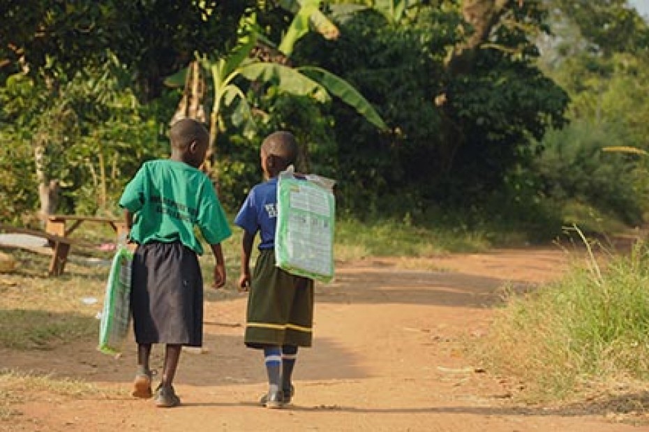 Two children walking on a dirt path.