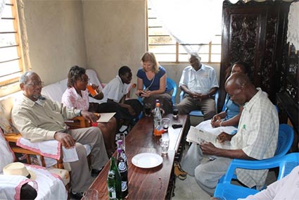 group of adults sitting around a table reading letters and enjoying a soft drink