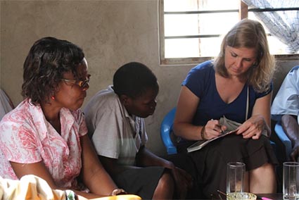 woman writing on a piece of paper as a girl and a woman look on