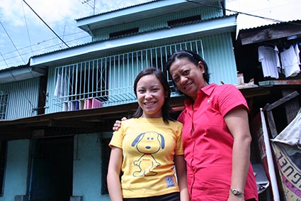 two women standing in front of a blue building