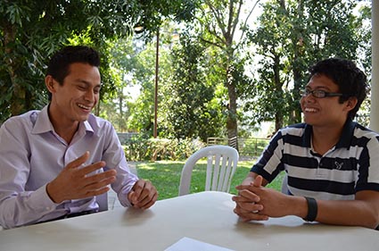 two young men sitting at a table laughing