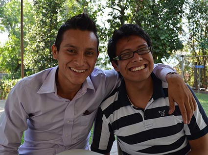 two smiling young men with one putting his arm around the other