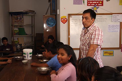 man standing with children sitting at a table