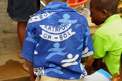 Back of a child wearing a blue uniform shirt with a center number and skippy image