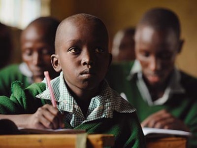 Three boys sitting at desks all wearing green sweaters