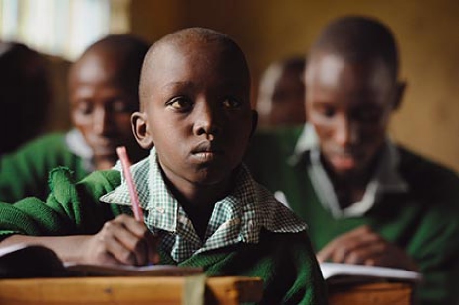 Three boys sitting at desks all wearing green sweaters