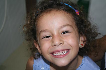 Young girl with curly hair showing her big smile after a dentist checkup