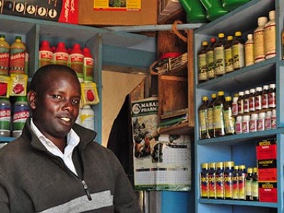 Man standing next to shelves with bottles.