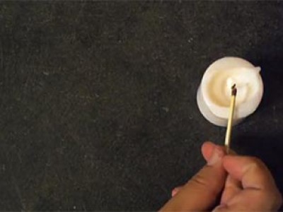 a hand lighting a white candle