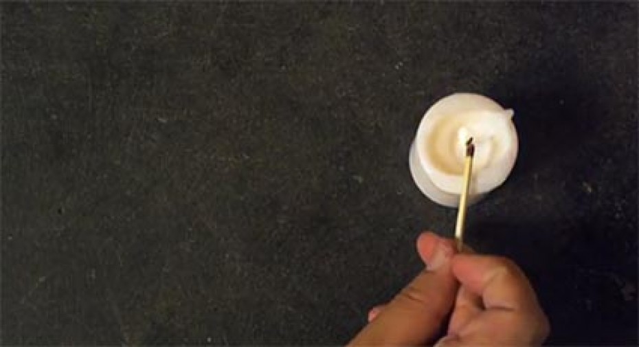 a hand lighting a white candle