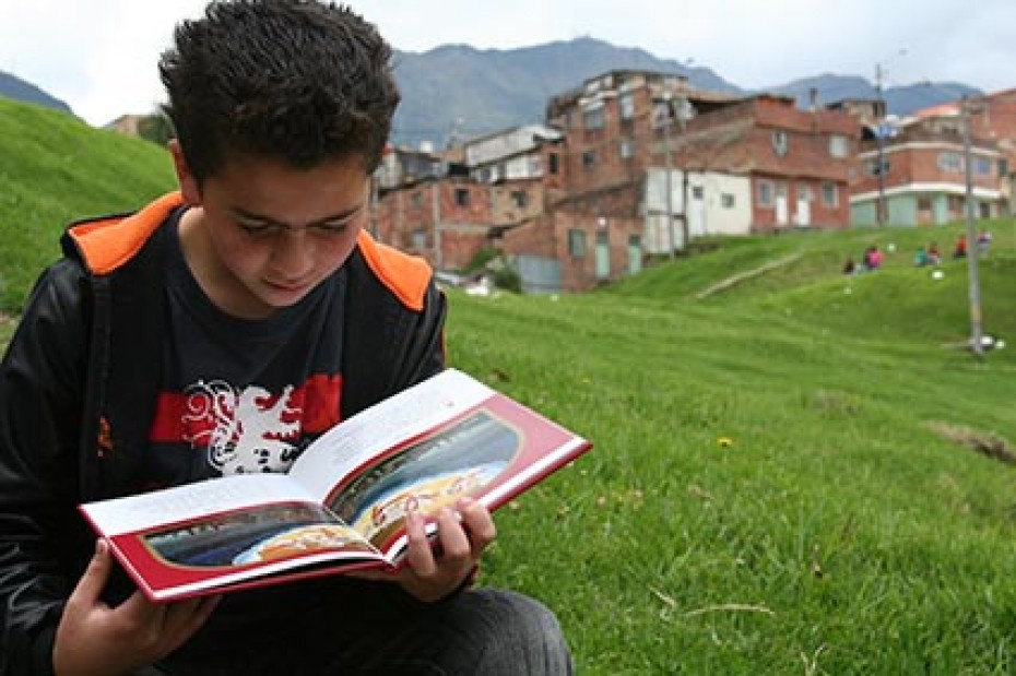 young boy sitting on ground reading
