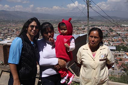 two women standing with another woman holding a small child