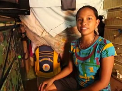 a girl sitting next to a dresser by a yellow backpack