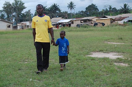 man in yellow shirt walking with small boy in blue shirt holding hands