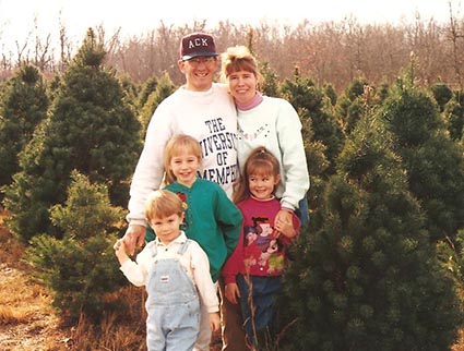 family standing in a Christmas tree lot