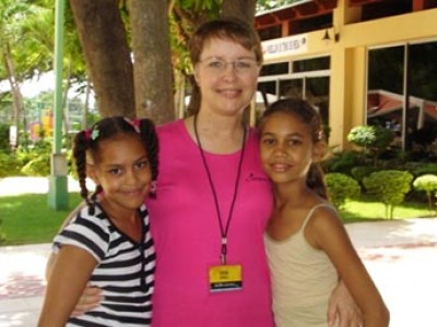 Two young ladies standing next to a woman.