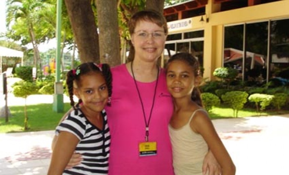 Two young ladies standing next to a woman.