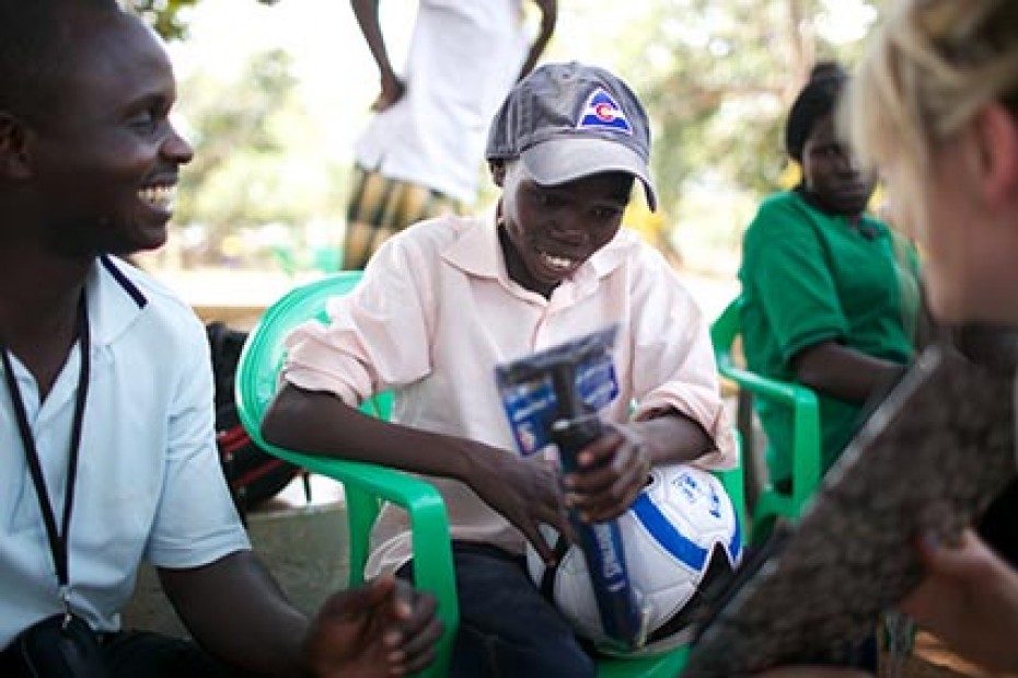 shy boy holding soccer ball being greeted by adults