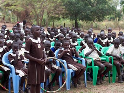 young girl standing and speaking in front of group of children