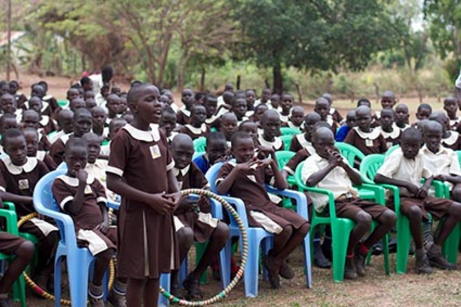 young girl standing and speaking in front of group of children