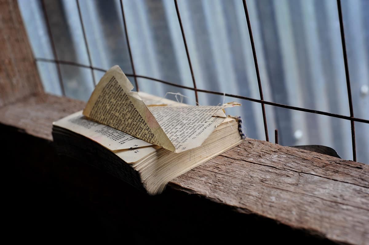 worn Bible on wooden shelf