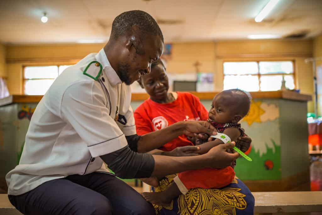 A doctor measures a child’s arm.