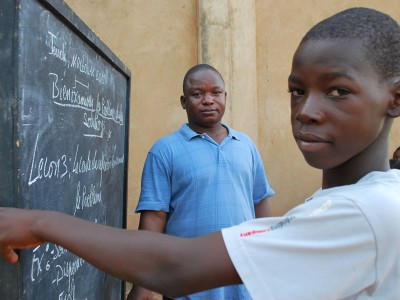 a boy standing in front of a chalkboard