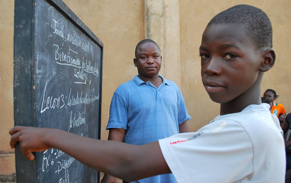 a boy standing in front of a chalkboard