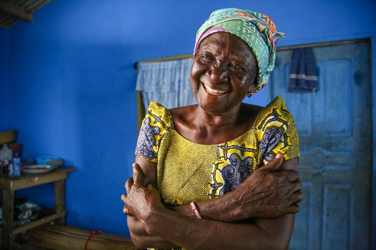 Ghanaian elder crossing arms while smiling and looking off into the distance.