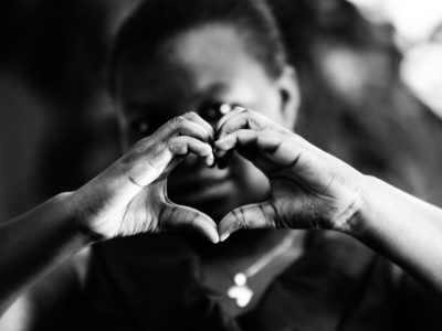 A child makes the shape of a heart with their hands