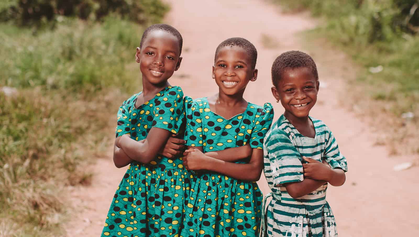 three smiling girls in green dresses