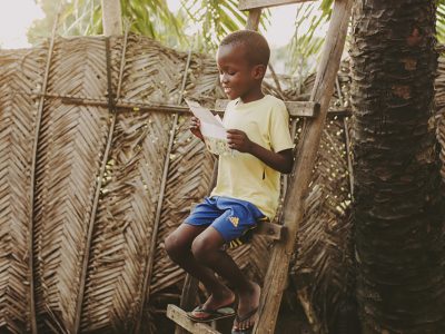 little boy sitting on ladder reading a letter