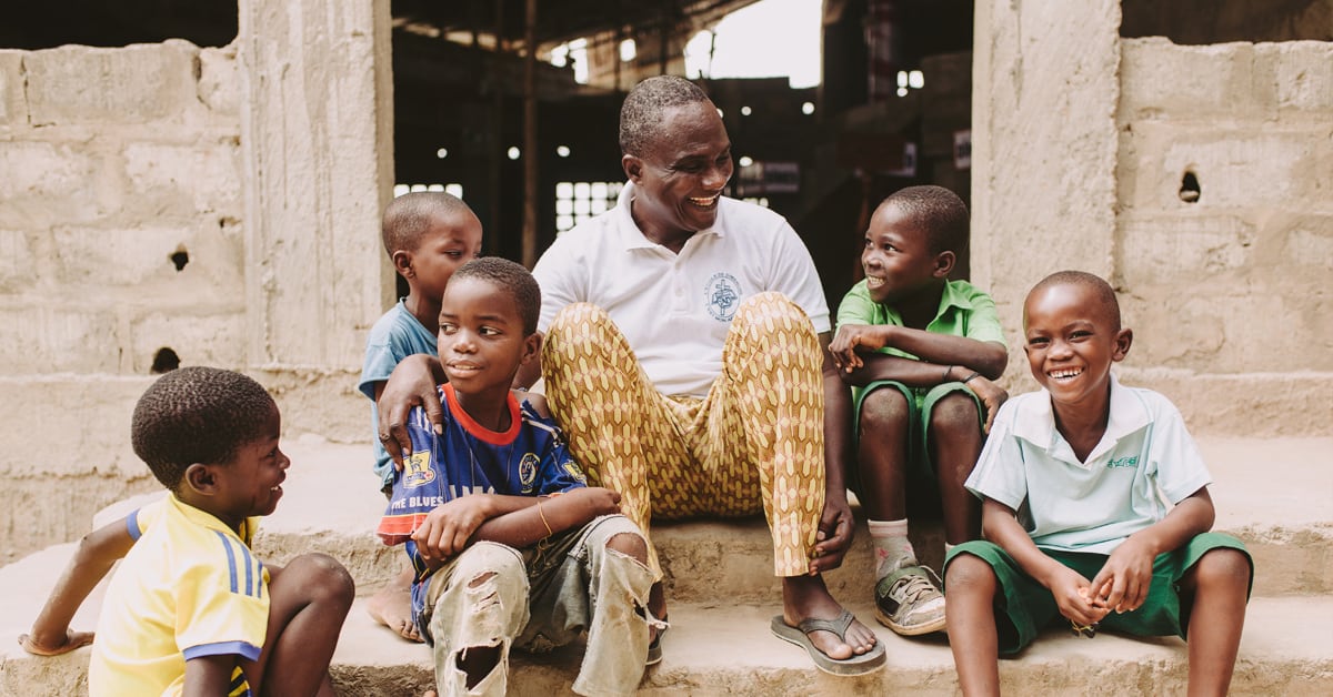 man sitting on step with five children around him