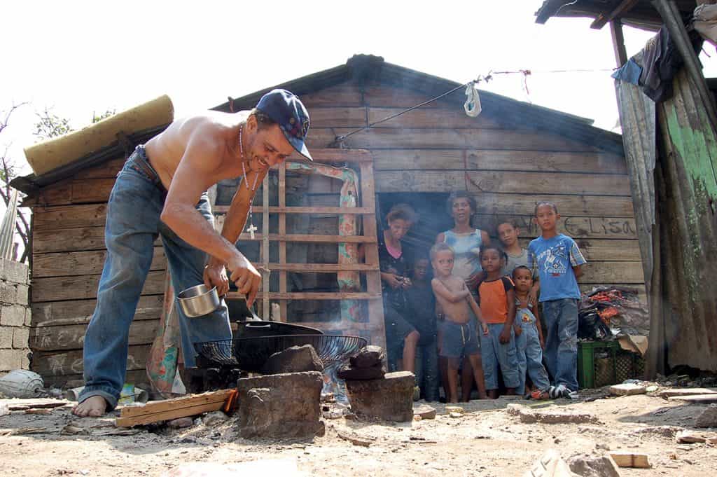 A father cooks for his family outside their tiny home in the Dominican Republic
