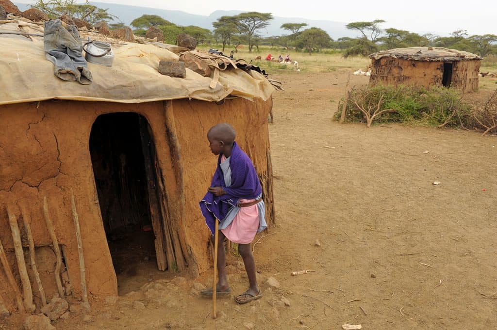 A Maasai boy in Kenya gets ready to enter a tiny home made of mud.