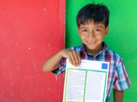 smiling boy holding a letter from sponsor