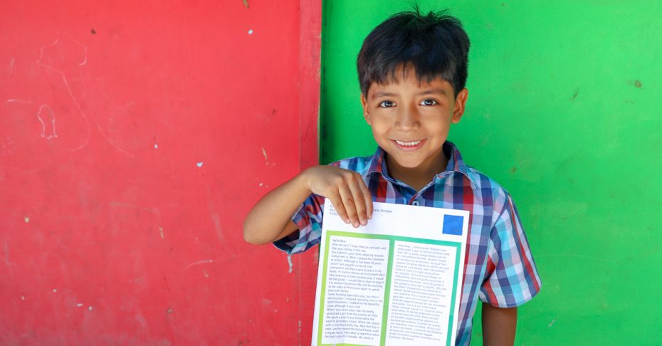 smiling boy holding a letter from sponsor